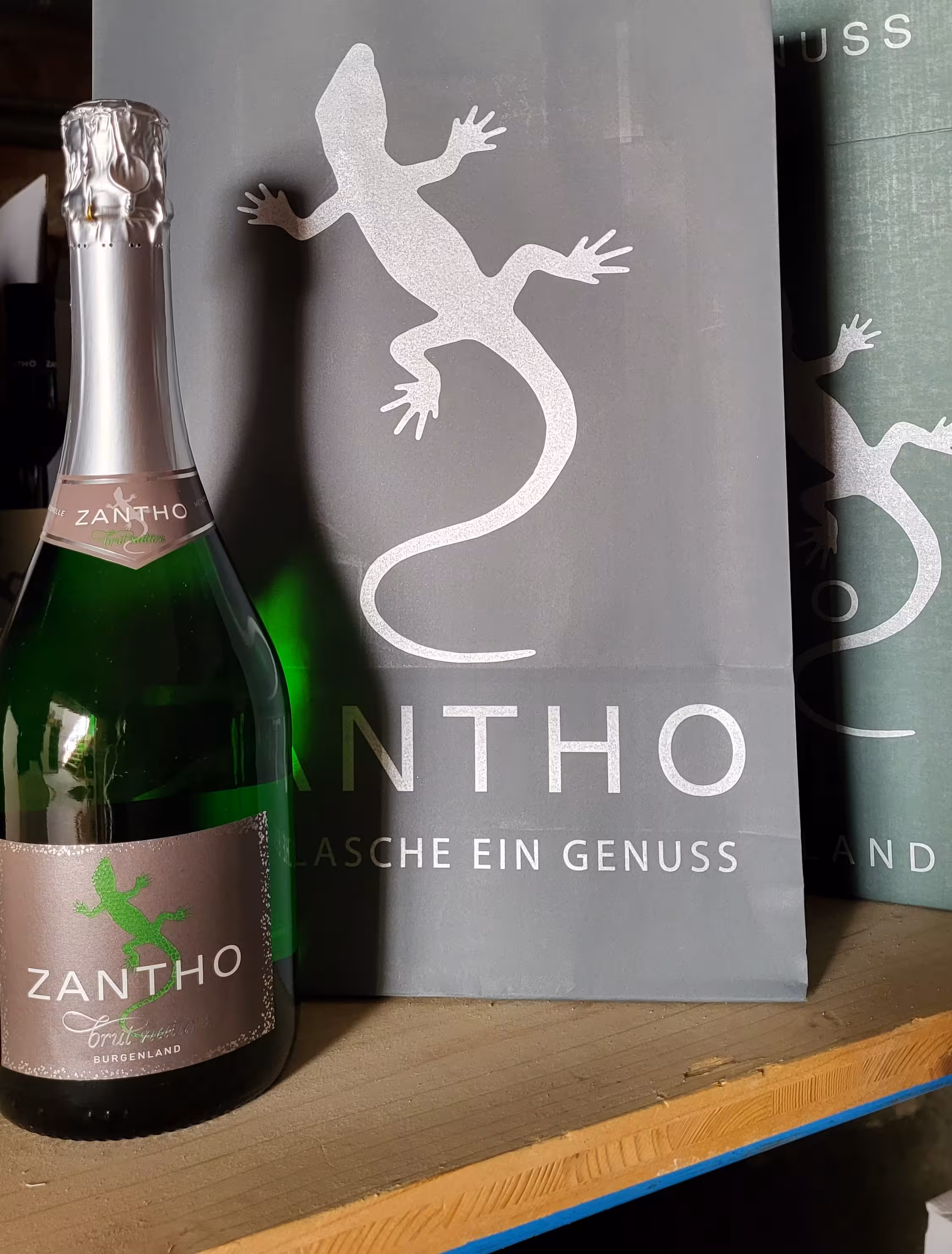 Zantho Sekt in der Flasche, fotografiert vor Zantho Tragetaschen